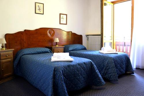 two beds in a hotel room with blue sheets at Hotel La Quiete in Bardonecchia