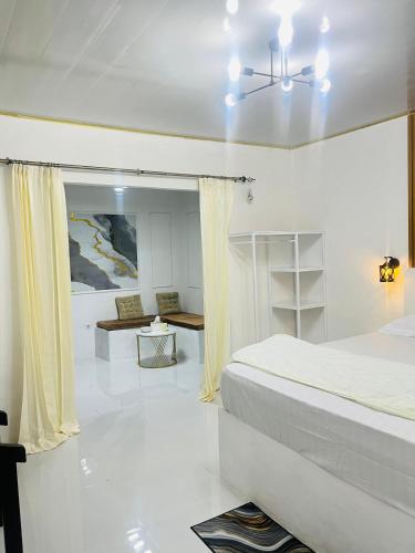 a white bedroom with a bed and a table at Mercy Cottage in Langgur