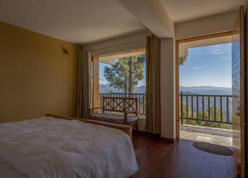 a bedroom with a bed and a balcony with a view at Kasar Rainbow Yoga Retreat in Hawālbāgh