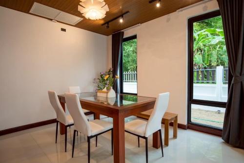 a dining room with a glass table and white chairs at P Square Villa in Ban Krabi Yai