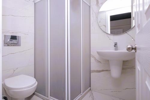 a white bathroom with a toilet and a sink at Muskebi Apart Otel in Ortakent