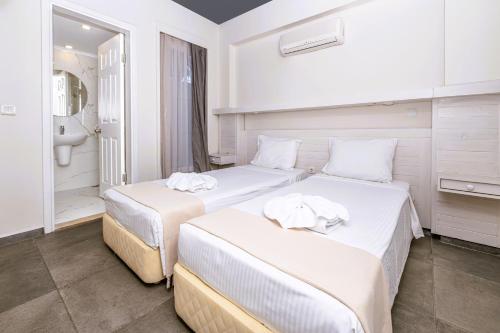 two beds in a room with a bathroom at Muskebi Apart Otel in Ortakent