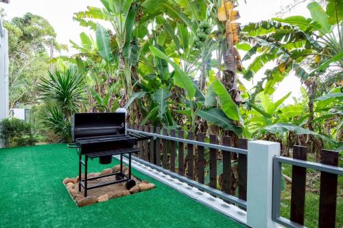 a black piano sitting on a lawn next to a fence at P Square Villa in Ban Krabi Yai