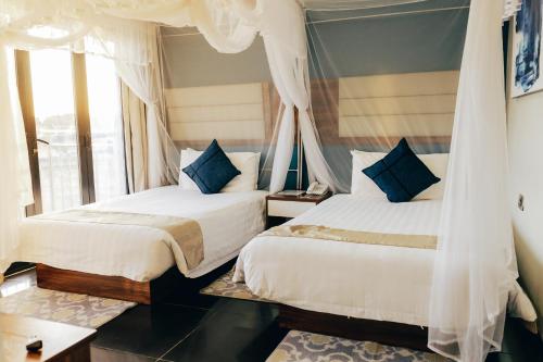 two beds in a room with a window at Sigelege Beach Resort in Senga