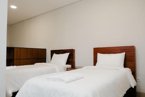 two beds in a room with white sheets at Hau Batu Karas in Batukaras
