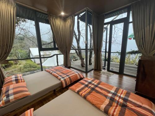 a bedroom with a bed and large windows at Vuon Hong Le Phuc-Cau Dat Glamping Retreat Da Lat in Ấp Trạm Hành