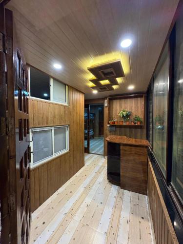 a room with wooden flooring and a kitchen with windows at Bunk Stays in Darjeeling