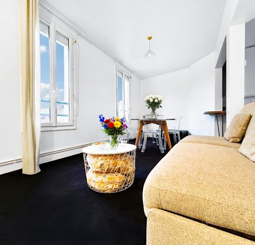 a room with a bed and a table with flowers on it at Superbe T3 familial et rénové au cœur de la ville - Proche Paris in Alfortville