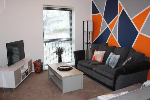 a living room with a couch and a tv at RestWorkPlayShortStays apartment, free parking and wifi, perfect for contractors, near to i54 park and city centre in Wolverhampton