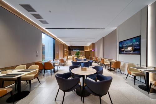 a restaurant with tables and chairs and windows at Echarm International Hotel Guangzhou Huangpu Flagship Shuixi Subway Station Branch - Free Deliver Service to Guangzhou Baiyun International Airport & Free Deliver Service to Canton Fair Complex During Canton Fair Period in Guangzhou