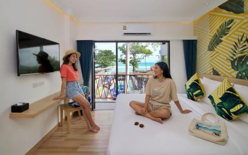two women sitting on a bed in a room at Lub d Koh Samui Chaweng Beach - Beachfront & Vibrant Social Vibe in Chaweng