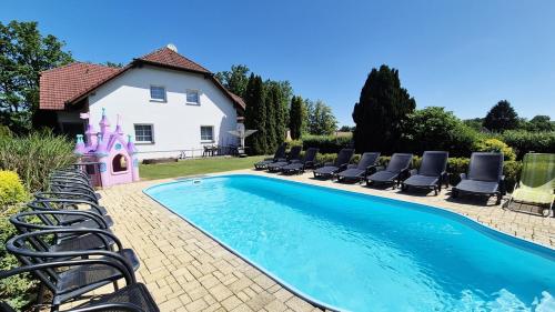 a swimming pool with lounge chairs and a house at Ubytování Mája in Třeboň