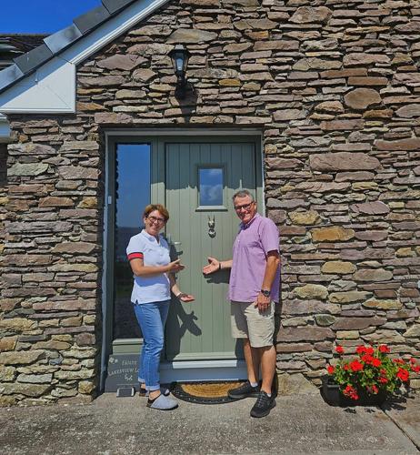 a man and a woman standing in front of a stone building at B&B Kerry Lakesview Lodge in Waterville