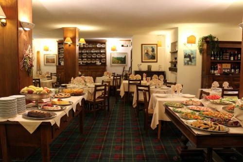 a dining room with tables filled with food at Hotel La Quiete in Bardonecchia