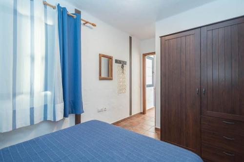 a bedroom with a blue bed and a wooden cabinet at GuestReady - Marea La Graciosa relax para familias in Caleta de Sebo