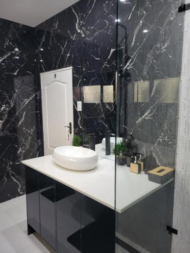 a bathroom with a sink and a black marble wall at Muyeni BnB in Harare