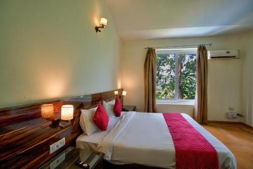 a bedroom with a bed with red pillows and a window at Aveeno Resort with Swimming Pool and Jacuzzi Near Calangute and Baga in Sangolda