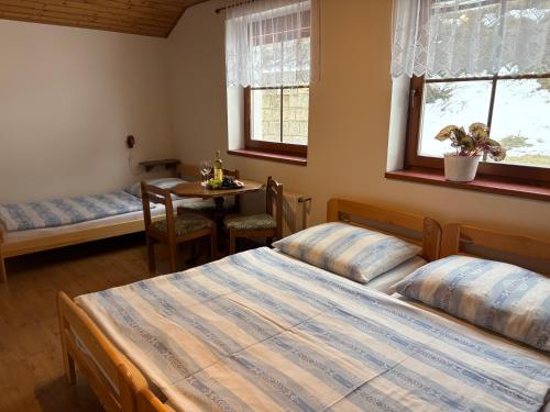 a bedroom with two beds and a table and two windows at Penzion Hamštejn in Koberovy