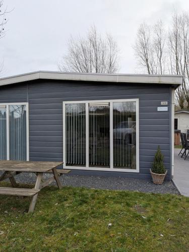 a gray garage with a picnic table and a bench at Bright Holiday Home with Hot Tub Near Breda in Molenschot