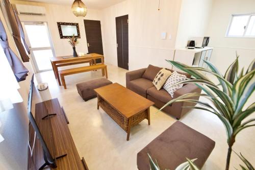 a living room with a couch and a table at Sunstone GINOWAN 1F in Futemma