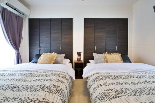 two beds sitting next to each other in a bedroom at Sunstone GINOWAN 1F in Futemma