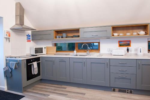 a kitchen with gray cabinets and a sink at Dartmoor Barn on North Hessary Tor in Yelverton