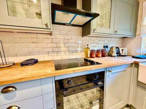 a kitchen with white cabinets and a stove top oven at Style 3BR House Jameston | Garden | Near Tenby in Tenby
