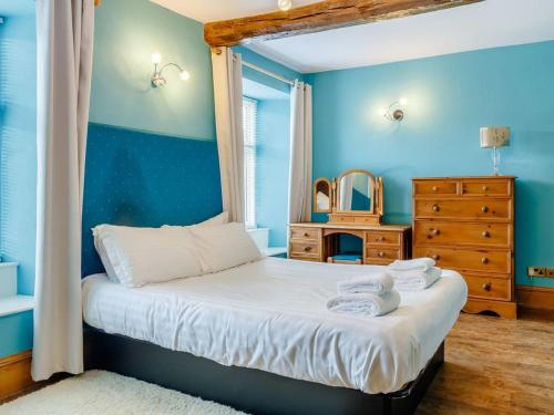 a bedroom with blue walls and a bed with towels on it at Henrhiw Farm House at Henrhiw Farm Cottages in Usk