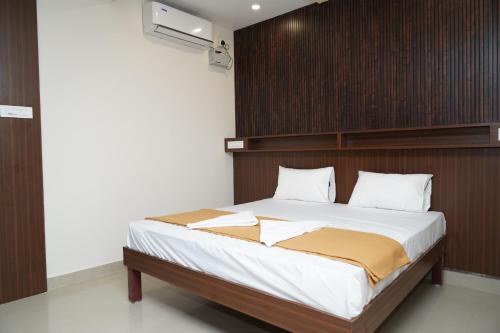 a bedroom with a large bed with a wooden headboard at DD COZY INN sntower in Tiruchirappalli