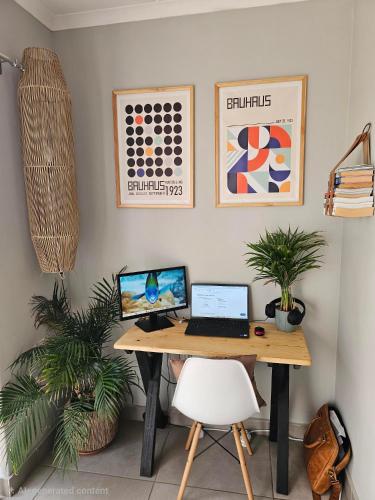 a desk with a laptop computer on it next to two plants at Quarter 5, Two Zero Four in Oakdale
