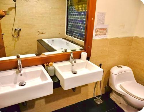 a bathroom with two sinks and a toilet and a mirror at Vimalla Hills 2br Private pool, bebas Jam cekin, cekout sesuai jam cekin 24 jam,081tiga80satu6415satu in Gadok 1