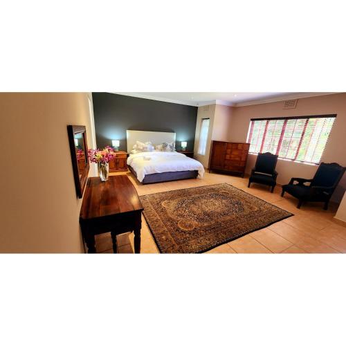 a bedroom with a bed and a desk and chairs at Gorgeous Garden Villa 3 in Gillitts-Emberton