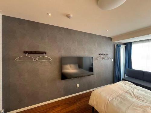 a bedroom with a bed and a tv on a wall at Eko House in 横浜石川町駅 in Yokohama