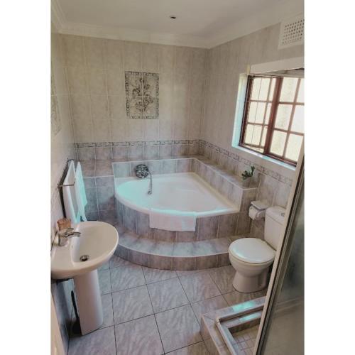 a bathroom with a tub and a toilet and a sink at Gorgeous Garden Villa 3 in Gillitts-Emberton