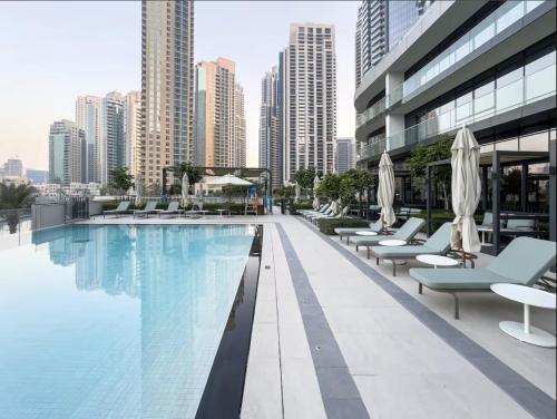 a swimming pool with chairs and umbrellas on a building at Private Room in Premium Burj Vista Downtown Apartment with Burj Khalifa View in Dubai
