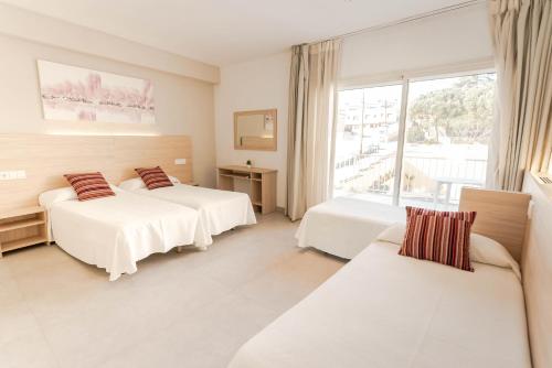 a hotel room with two beds and a window at Hotel S'Agoita in Platja d'Aro