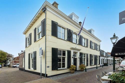 a white building with black shutters on a street at Steenhof Residence Warmond in Warmond