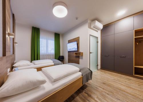 a bedroom with two beds and a television in it at Das schlaf&GUT - Self Check-In in Leibnitz