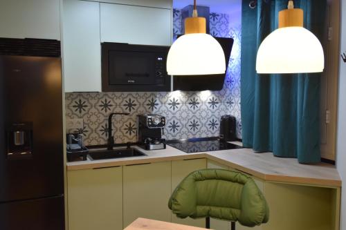 a kitchen with two pendant lights and a green chair at Resort Villa Las Palmeras in Roquetas de Mar