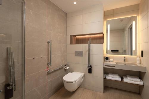 a bathroom with a toilet and a shower and a sink at AC Hotel by Marriott Inverness in Inverness