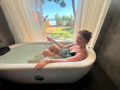 a woman sitting in a bath tub with a glass of wine at La Brisa By Harry Beach Villa in Dickwella