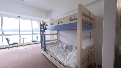a bunk bed in a room with a desk and chairs at 森口屋アートスクエア in Shodoshima