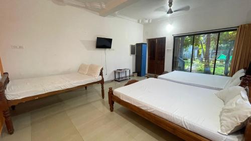 a room with two beds and a tv in it at CASA Lasa Beach view in Kālapettai
