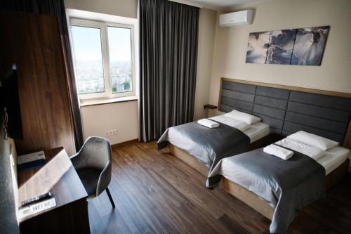 a hotel room with two beds and a desk at Nesvit Hotel in Kyiv