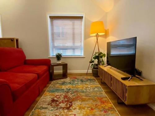 a living room with a red couch and a flat screen tv at 1BR Haven in Crewe - Modern, Chic & Central in Crewe