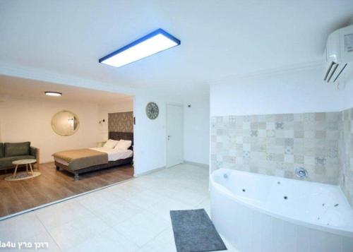 a bathroom with a tub and a bedroom with a bed at קסם הרימון - 4 צימרים מושלמים עם בריכה וג'קוזי in ‘Azriqam