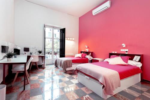 a pink bedroom with two beds and a desk at LoopINN Granada in Granada