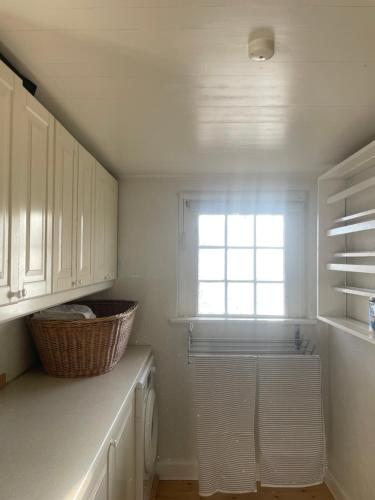 a kitchen with white cabinets and a window at Guest house Æbelnæs, Møn in Stege