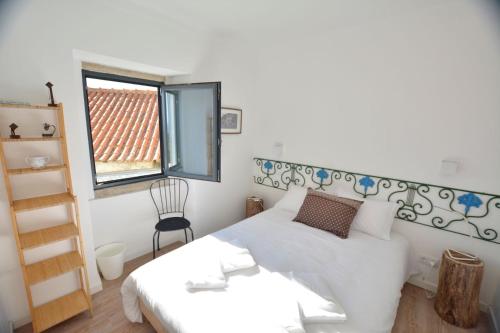 a bedroom with a white bed and a window at Casota in Sintra