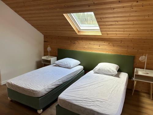 une chambre avec deux lits et un puits de lumière dans l'établissement Les Coteaux, à Gérardmer